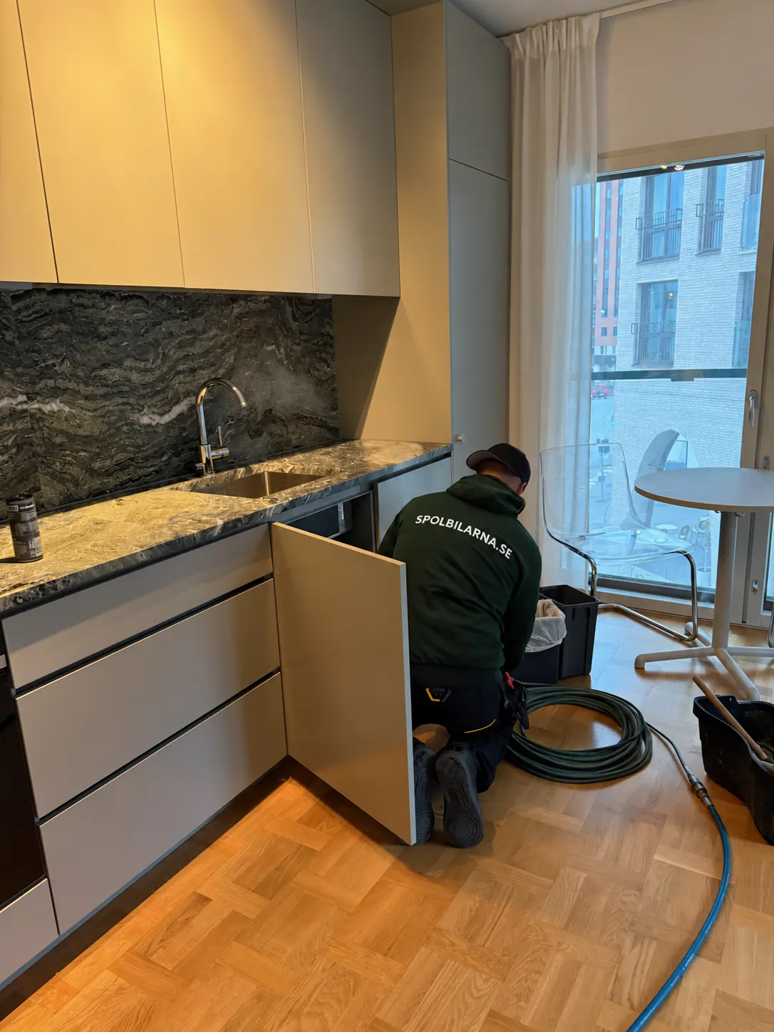 Tekniker från Spolbilarna rensar köksavloppet under diskbänken i en lägenhet – Spolbilarna i Mölndal