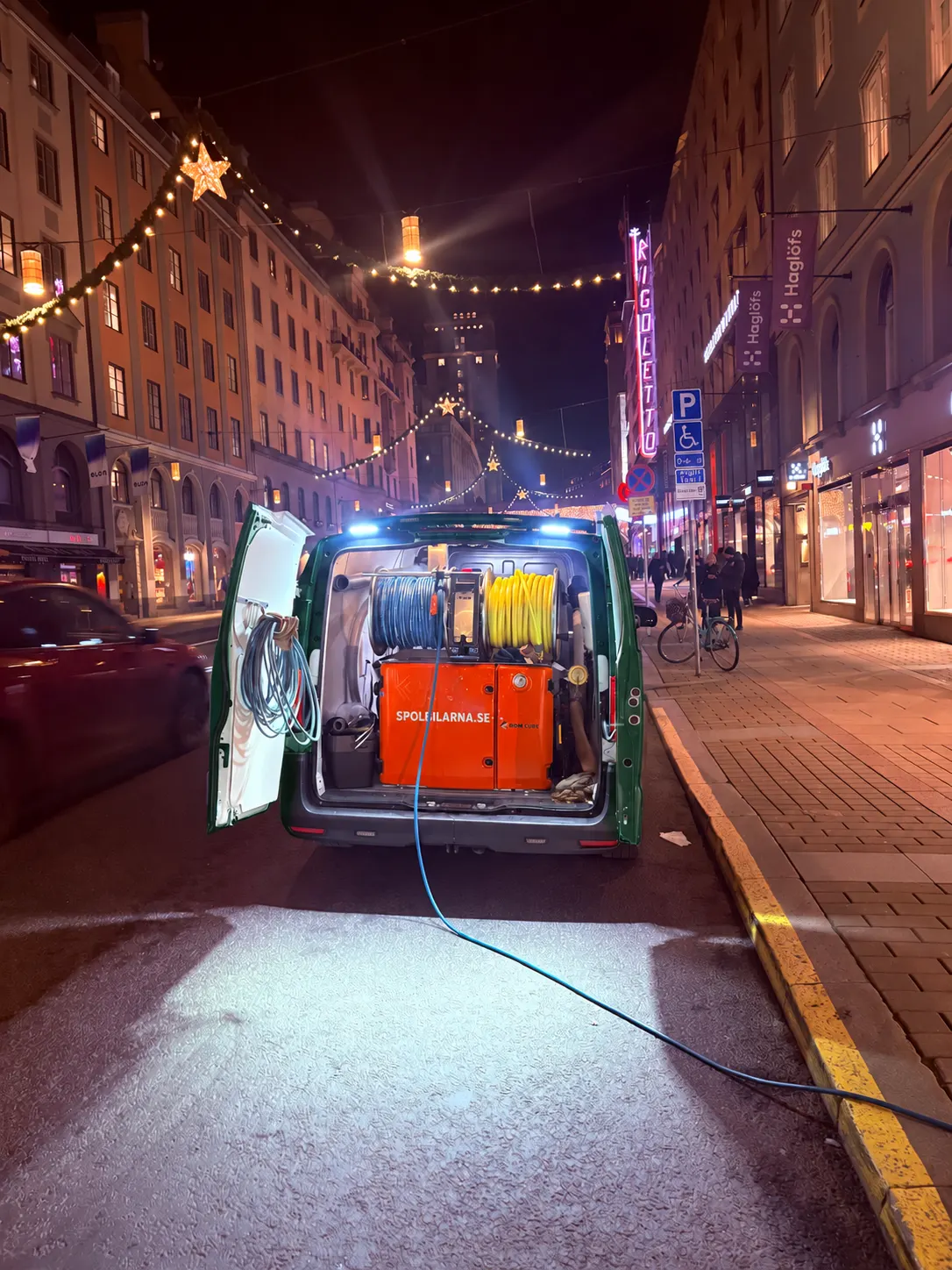 Spolbil med högtrycksaggregat och slangtrummor på ett kvällsuppdrag i centrala Stockholm