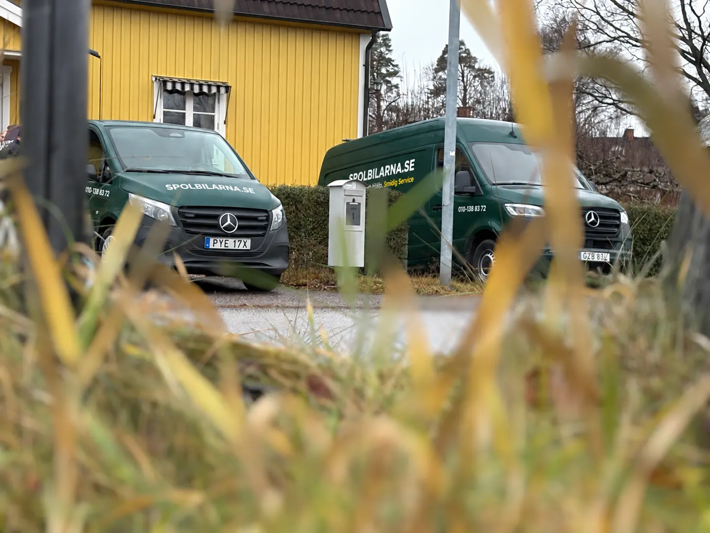 Två av Spolbilarnas servicebilar parkerade framför ett gult hus – Spolbilarna i Gråbo