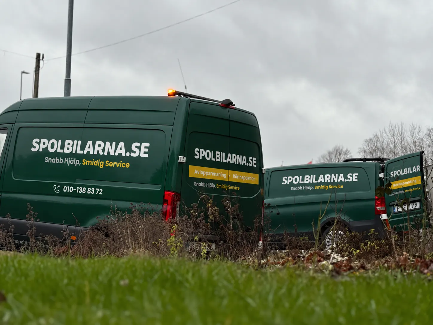 Två av Spolbilarnas servicebilar med logotyp och tjänster på dörrarna