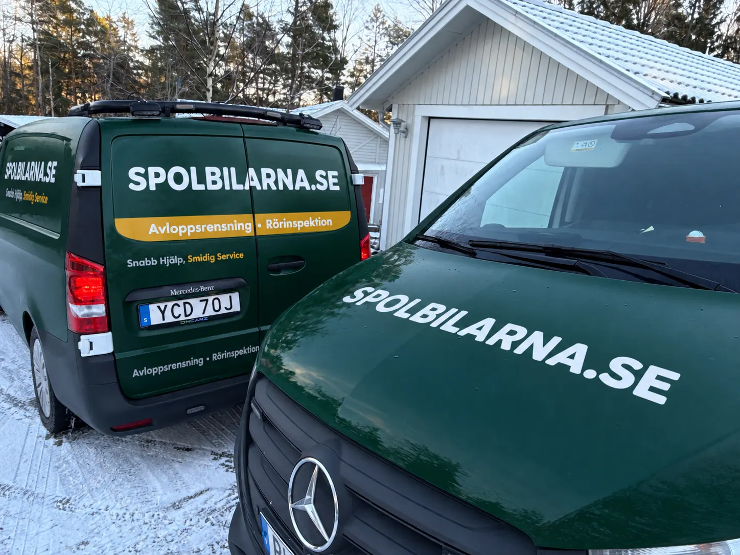 Två av Spolbilarnas servicebilar på en snötäckt uppfart – Spolbilarna i Smålandsstenar