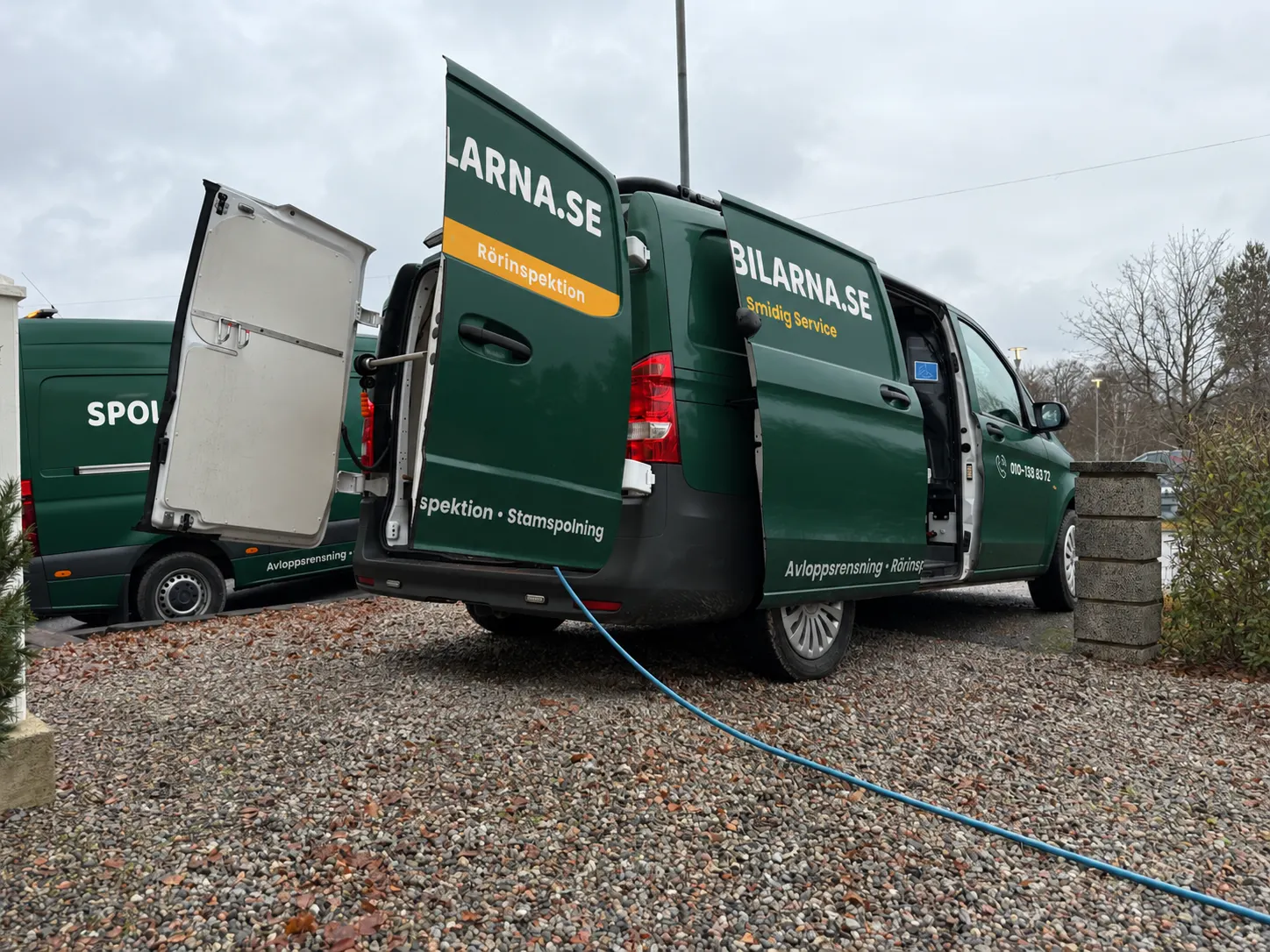 Spolbil från Spolbilarna med öppna dörrar och spolslangen utdragen på ett uppdrag